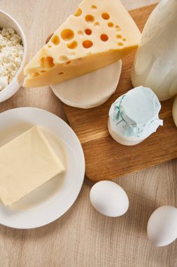 Tahta masadaki çeşitli taze organik süt ürünleri ve yumurtaların üst görüntüsü