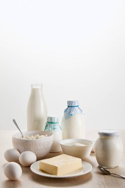 Tahta masadaki taze organik süt ürünleri ve yumurtalar beyaz üzerine izole edilmiş.
