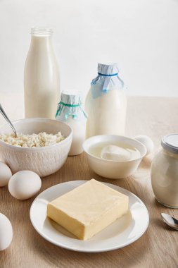 Tahta masadaki taze organik süt ürünleri ve yumurtalar beyaz üzerine izole edilmiş.
