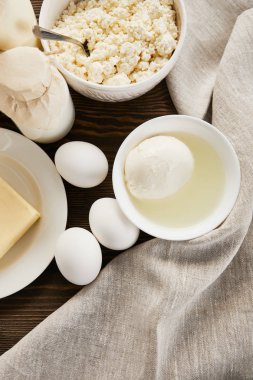 Lezzetli taze süt ürünleri ve kırsal ahşap masa üzerinde kumaşlı yumurtalar.