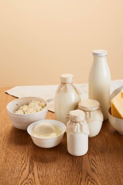 Bej üzerine izole edilmiş ahşap masa üzerindeki lezzetli organik süt ürünleri.