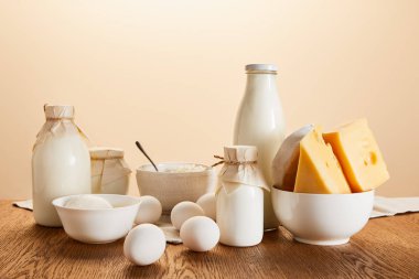 Lezzetli organik süt ürünleri ve kırsal ahşap masa üzerindeki yumurtalar bej renginde izole edilmiş.