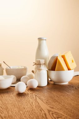 Lezzetli organik süt ürünleri ve kırsal ahşap masa üzerindeki yumurtalar bej renginde izole edilmiş.