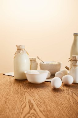 Lezzetli organik süt ürünleri ve kırsal ahşap masa üzerindeki yumurtalar bej renginde izole edilmiş.