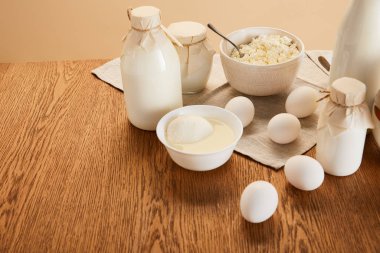 çeşitli organik süt ürünleri ve kırsal ahşap masa üzerindeki yumurtalar bej renginde izole edilmiş.