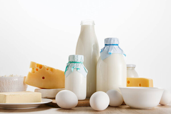 various fresh organic dairy products and eggs on wooden table isolated on white