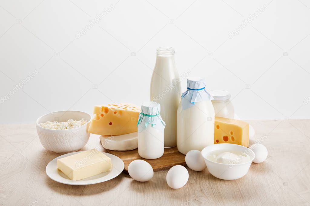 various fresh organic dairy products and eggs on wooden table isolated on white