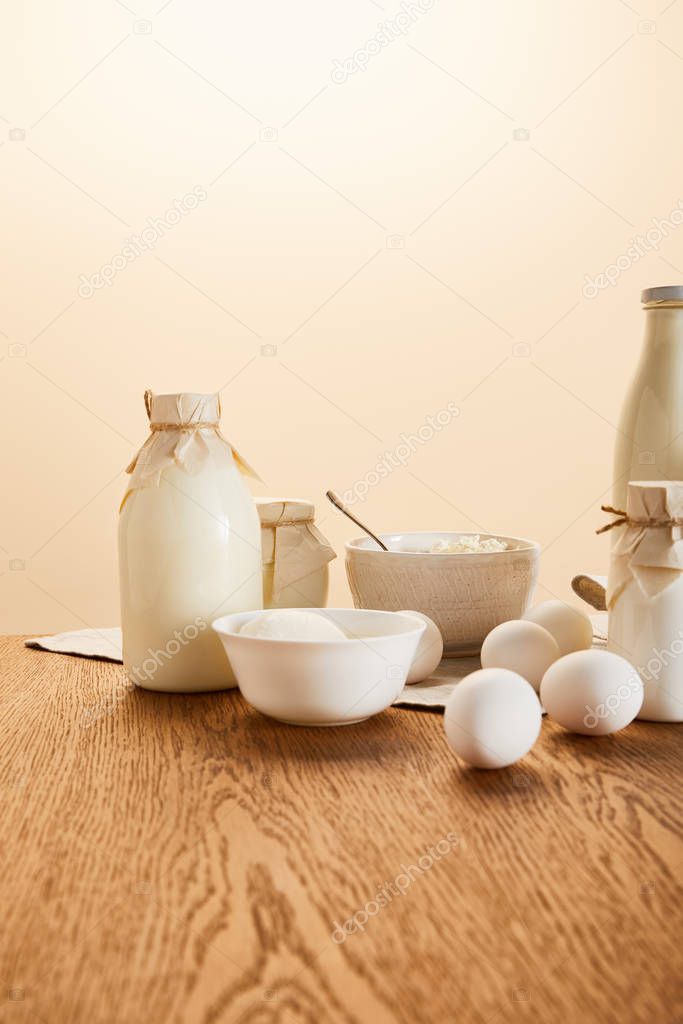 tasty organic dairy products and eggs on rustic wooden table isolated on beige