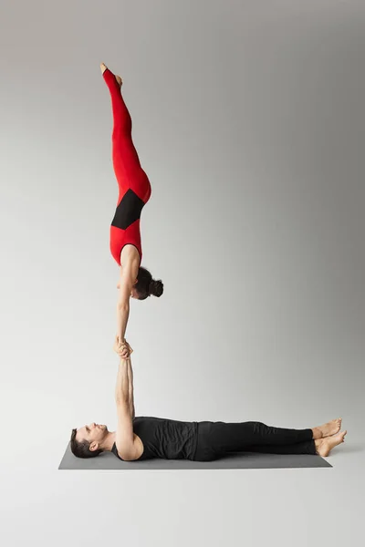 Pareja Joven Practicando Acroyoga Estera Yoga Estudio Aislada Sobre Gris — Foto de Stock