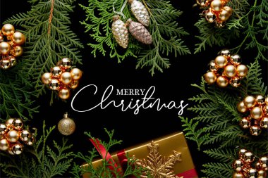 Parlak altın noel süslemeleri, yeşil thuja dalları ve siyah üzerine izole edilmiş hediye kutusu Mutlu noeller illüstrasyonu.