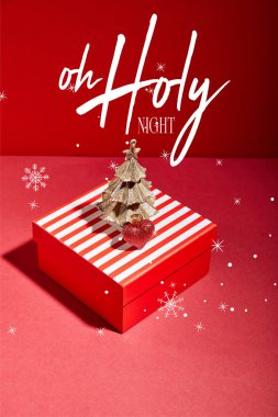striped red gift box and decorative golden Christmas tree with bauble on red background with o holy night illustration clipart