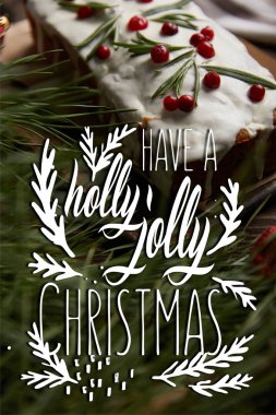 Geleneksel Noel pastasının seçici odağı, çam ağacının yanında kızılcık ve kutsal bir Noel çizimi var.