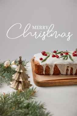 Geleneksel Noel pastası, yaban mersinli ve çam ağacından yapılma gri masa ve Mutlu Noeller illüstrasyonu.
