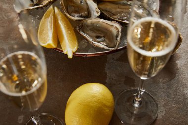 selective focus of oysters and lemons in bowl with ice near champagne glasses with sparkling wine  clipart