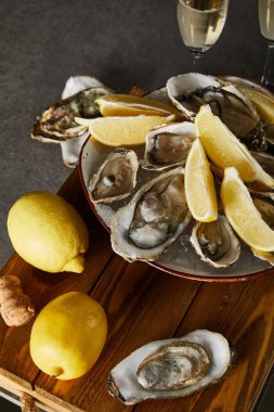 Limonların seçici odak noktası istiridye kasesi ve gri yüzeyde şampanya bardakları. 