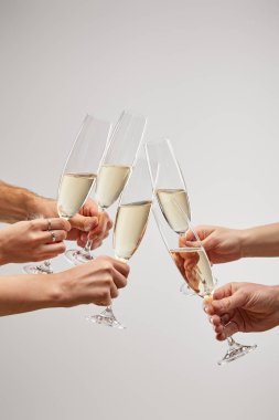 cropped view of men and women toasting champagne glasses with sparkling wine isolated on grey  clipart