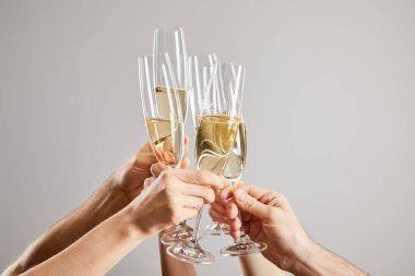 cropped view of men and women toasting champagne glasses with fresh sparkling wine isolated on grey  clipart