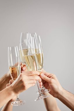 cropped view of women and men toasting while holding champagne glasses with sparkling wine isolated on grey  clipart
