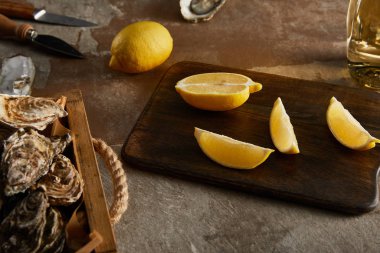Lezzetli istiridyelerin seçici odak noktası limonların yanında tahta kesme tahtasının üzerinde.