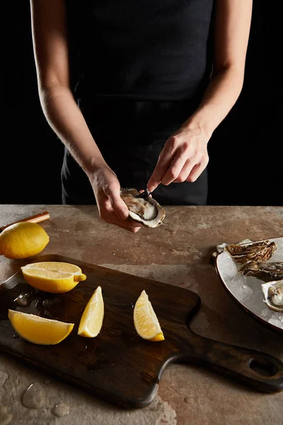 厨师在用黑色隔离的新鲜牡蛎附近拿着叉子的剪影 — 图库照片