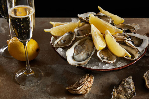 champagne glasses with sparkling wine near oysters and fresh lemons in bowl 