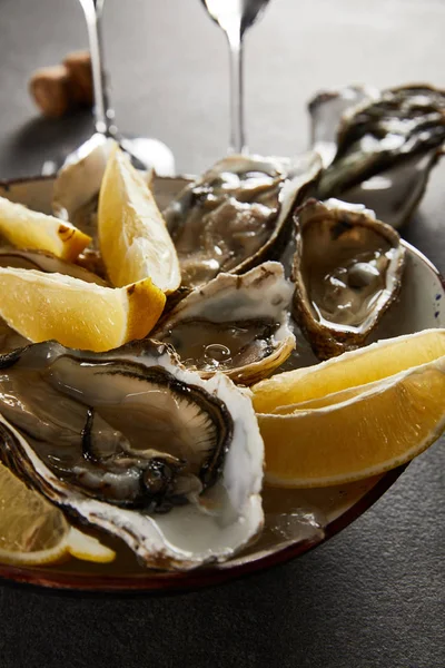 将美味的牡蛎和柠檬放在碗里 冰封在灰色的表面 — 图库照片