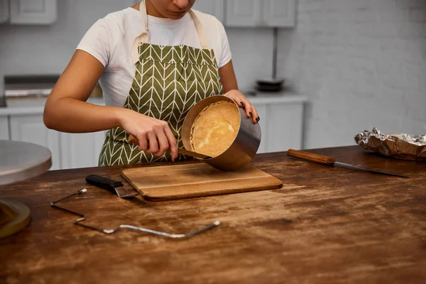 Cropped view of confectioner cutting cake from cake mold