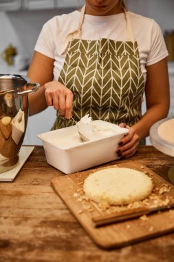 Confectioner taking cream for cooking cake in kitchen  clipart