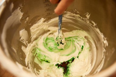 Cropped view of confectioner mixing sweet cream in bowl clipart