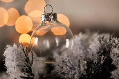Süslü, şeffaf noel balosu ladin dallarında, karda, bulanık sarı ışıklarla.