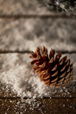 close up of pine cone on wooden table with snow on christmas clipart