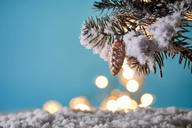Karda Noel ağacı, dekoratif çam kozalağı ve Noel ışıkları mavi renkte bohçalanır.