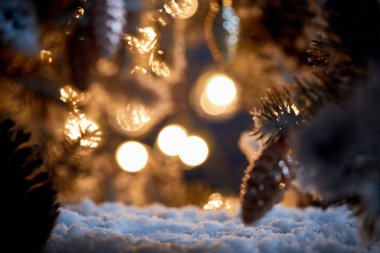 Noel ağacını kapatın. Karda dekoratif noel topları ve karanlıkta bulanık ışıklar olsun. 