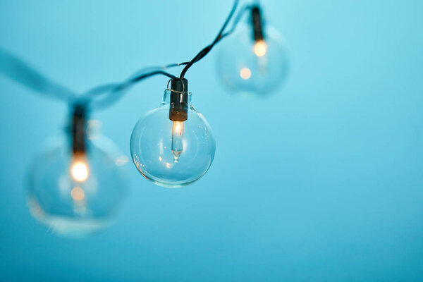 close up of christmas garland with transparent light bulbs isolated on blue