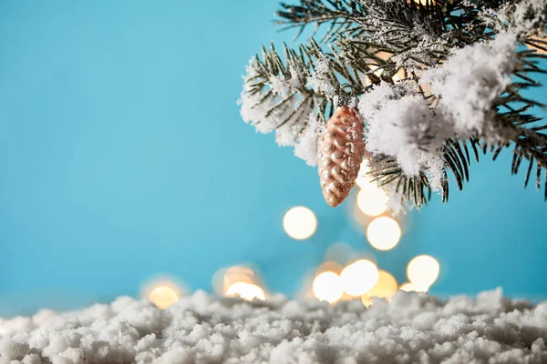 Tannenbaumzweige Schnee Mit Dekorativem Tannenzapfen Und Weihnachtsbeleuchtung Bokeh Auf Blau — Stockfoto