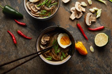 Kavanozlu geleneksel baharatlı ramen ve taş yüzeyinde sebzeler.