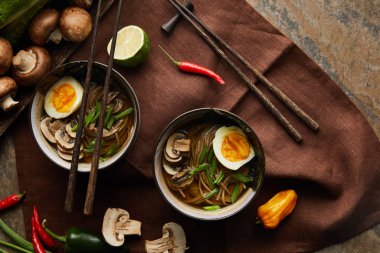 Kavanozlu geleneksel baharatlı ramen ve taş yüzeyde kahverengi peçeteli sebzeler.