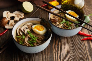 Kavanozlu geleneksel baharatlı ramen ve peçeteli ahşap masada sebzeler.
