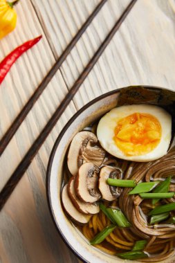 Geleneksel baharatlı ramen tabakta ahşap masada yemek çubuklarının yanında.