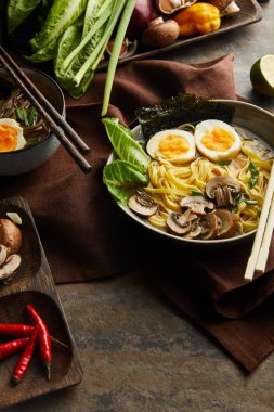 Kavanozlu geleneksel baharatlı ramen ve taş yüzeyde kahverengi peçete.