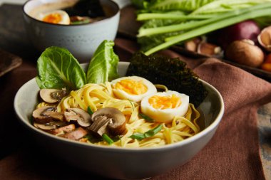 Kavanozda geleneksel baharatlı ramen, taş yüzeyde kahverengi peçete.