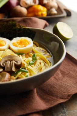 Geleneksel baharatlı ramen tabakta, taş yüzeyde kahverengi peçete üzerinde.
