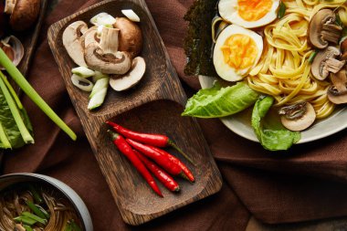 Tabaklarda geleneksel baharatlı ramen ve taş yüzeyinde kahverengi peçete.