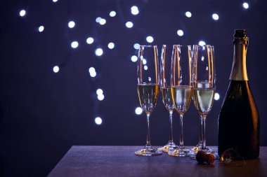 Şampanya şişede ve bardaklar mavi noel ışıkları bokeh