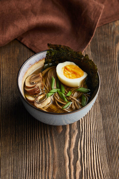 traditional spicy ramen in bowl on wooden table with napkin