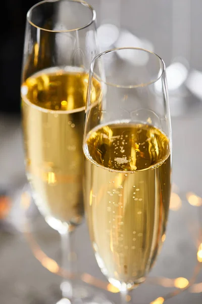 用模糊的黄色圣诞彩灯近照玻璃杯中闪闪发光的葡萄酒 — 图库照片