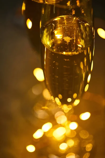 用模糊的黄色圣诞彩灯近照玻璃杯中闪闪发光的葡萄酒 — 图库照片
