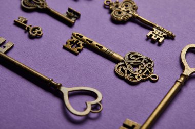 close up view of vintage keys on violet background clipart