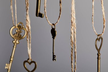 close up view of vintage keys hanging on ropes isolated on grey clipart