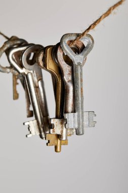 close up view of vintage rusty keys hanging on rope isolated on white clipart